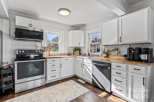 kitchen featuring dark wood-style floors, white cabinetry, stainless steel appliances, and crown molding