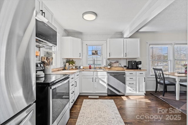 kitchen featuring dark wood-style floors, appliances with stainless steel finishes, white cabinets, and a sink