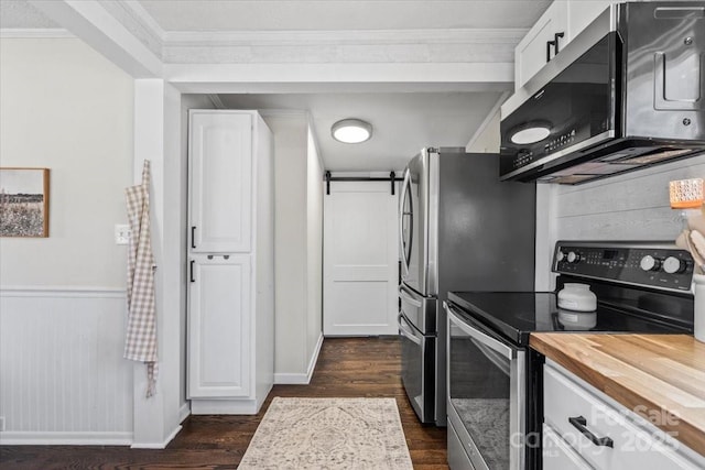 kitchen with a barn door, appliances with stainless steel finishes, ornamental molding, white cabinetry, and wooden counters