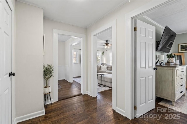 corridor with dark wood-style floors, baseboards, and crown molding