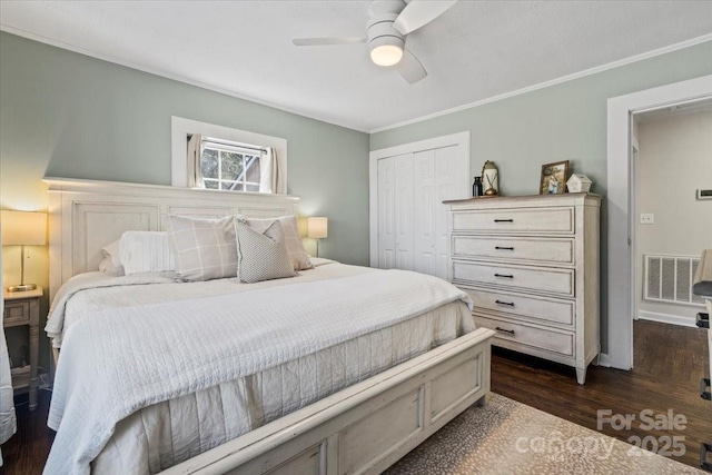 bedroom featuring dark wood-style floors, crown molding, a closet, visible vents, and ceiling fan