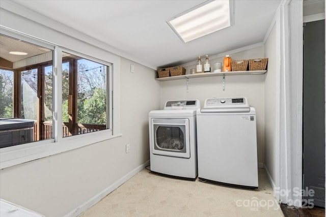 laundry area featuring washing machine and dryer, laundry area, baseboards, light floors, and crown molding