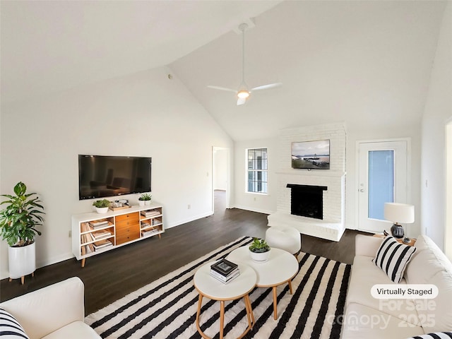 living area featuring baseboards, a ceiling fan, wood finished floors, a fireplace, and high vaulted ceiling