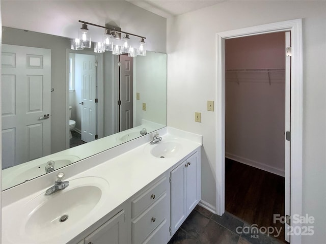 bathroom featuring double vanity, a sink, and toilet