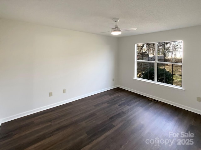 unfurnished room with dark wood-style flooring, visible vents, a ceiling fan, a textured ceiling, and baseboards