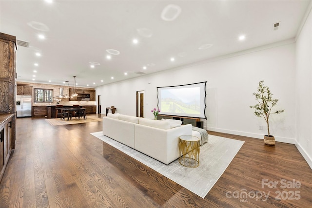 living room with dark wood-style floors, recessed lighting, visible vents, and ornamental molding