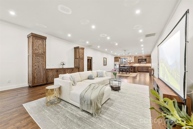 living room featuring baseboards, visible vents, dark wood-style floors, ornamental molding, and recessed lighting