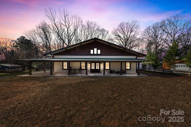 back of property at dusk with a patio, a lawn, and fence