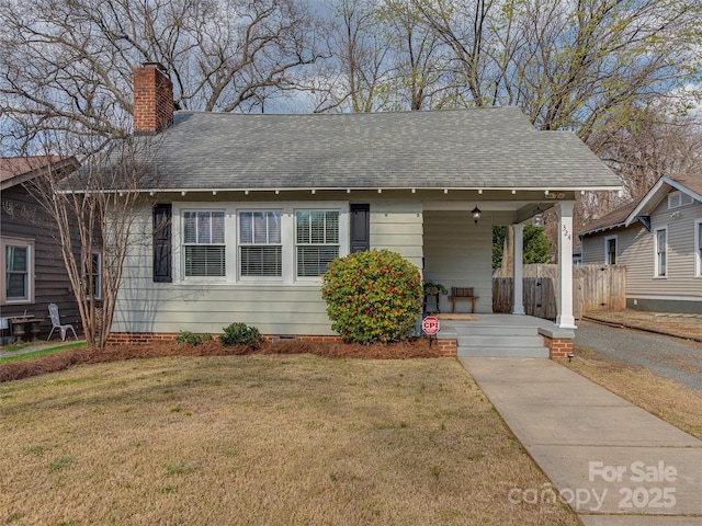 view of front facade with roof with shingles, a chimney, a porch, a front yard, and crawl space