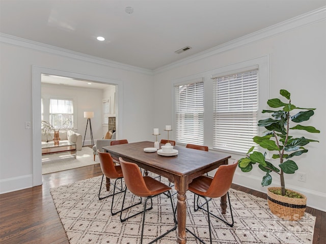 dining room featuring ornamental molding, visible vents, baseboards, and wood finished floors