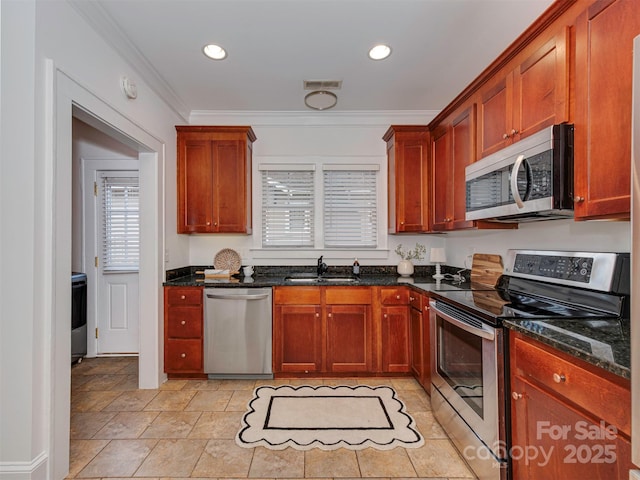 kitchen with stainless steel appliances, a sink, visible vents, dark stone countertops, and crown molding