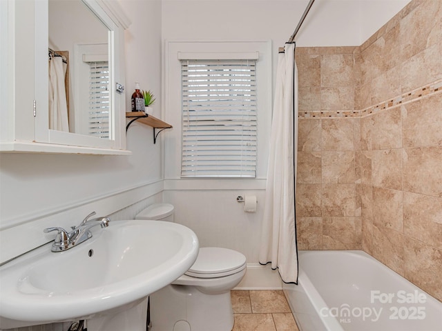 bathroom featuring shower / bath combination with curtain, a sink, and toilet