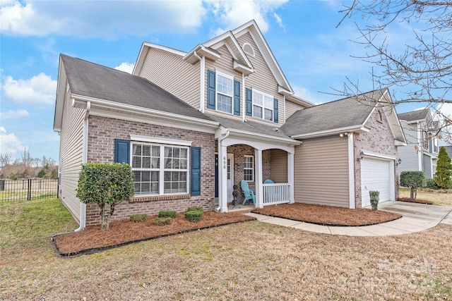 view of front of home with brick siding, a porch, concrete driveway, fence, and a front lawn