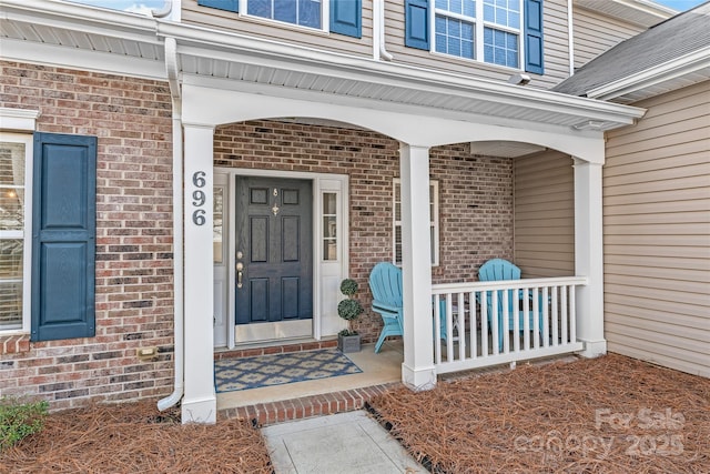 doorway to property with covered porch and brick siding