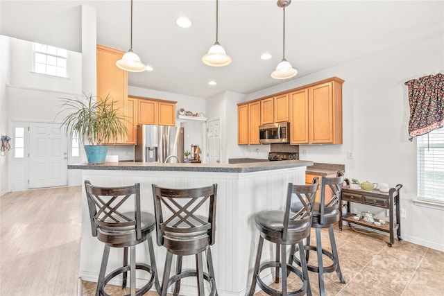 kitchen with dark countertops, a kitchen bar, and appliances with stainless steel finishes