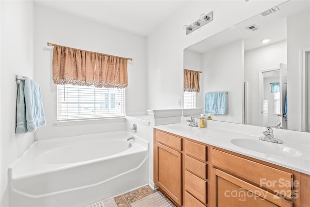 bathroom featuring a bath, double vanity, visible vents, and a sink