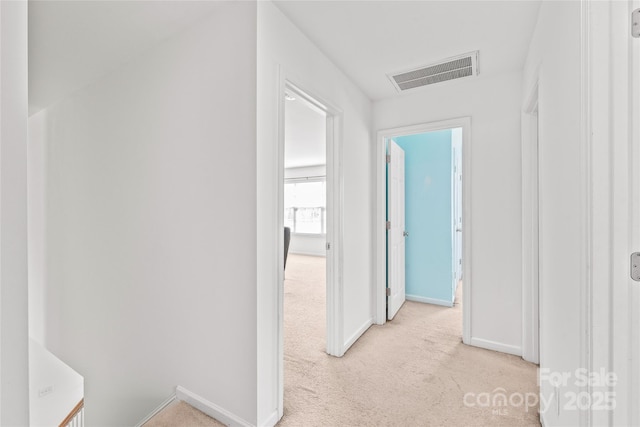 hall featuring light colored carpet, visible vents, and baseboards