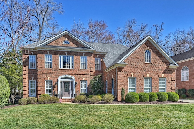 colonial home featuring brick siding and a front lawn