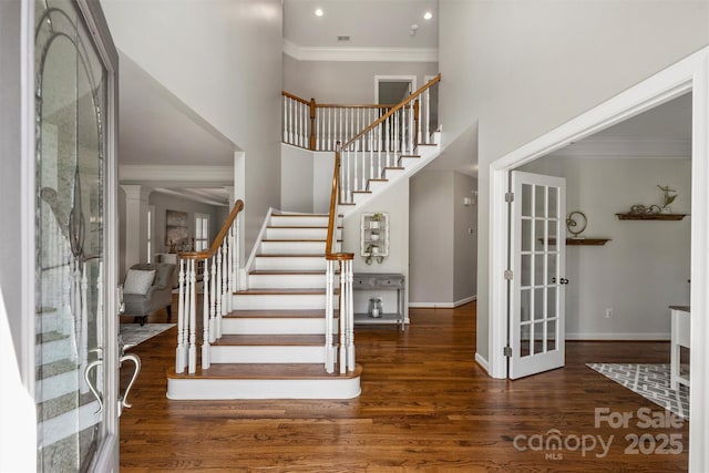 foyer entrance with ornamental molding, stairway, wood finished floors, and baseboards