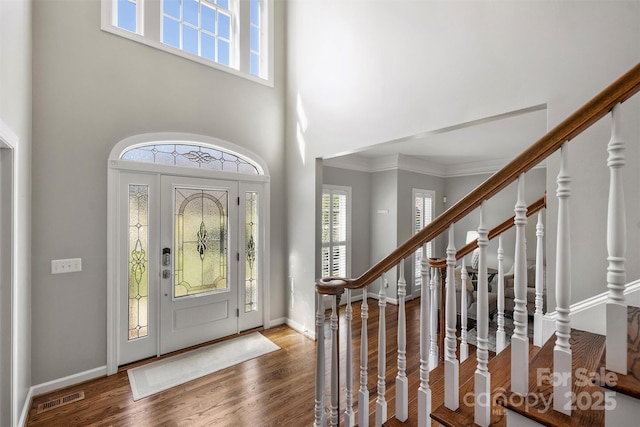 foyer entrance with stairway, baseboards, visible vents, and wood finished floors