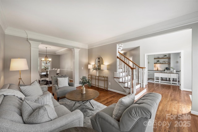 living room with stairway, wood finished floors, decorative columns, and a notable chandelier