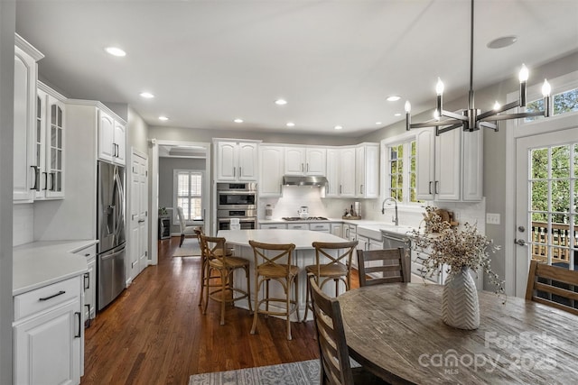 kitchen with white cabinets, decorative backsplash, dark wood-style floors, stainless steel appliances, and a healthy amount of sunlight