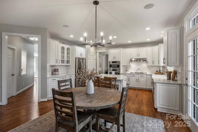 dining space featuring a chandelier, dark wood-style flooring, baseboards, and recessed lighting