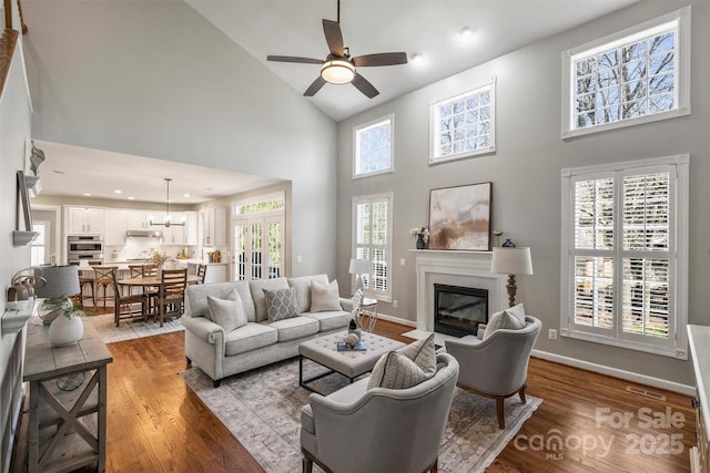 living area with light wood finished floors, a fireplace with flush hearth, visible vents, and baseboards