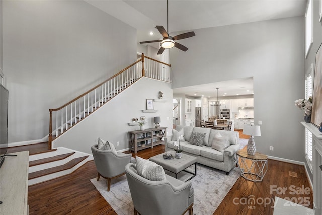 living room with a high ceiling, stairway, wood finished floors, and baseboards