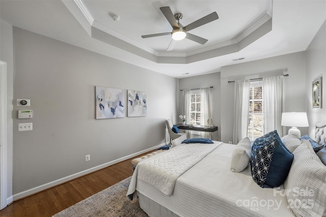 bedroom with ornamental molding, wood finished floors, a raised ceiling, and baseboards