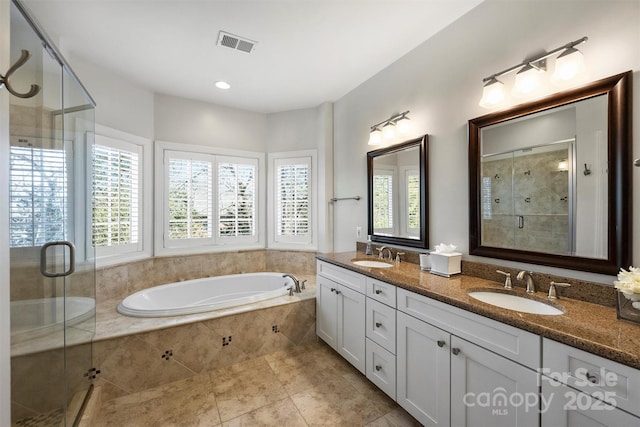 bathroom with a stall shower, visible vents, a sink, and a garden tub