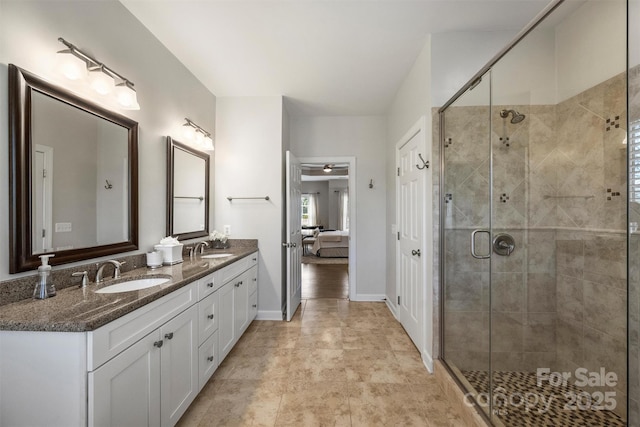 ensuite bathroom featuring double vanity, a shower stall, and a sink