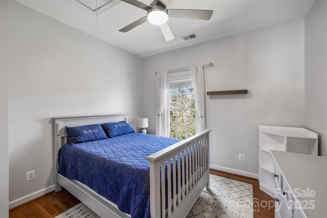 bedroom with visible vents, attic access, ceiling fan, wood finished floors, and baseboards