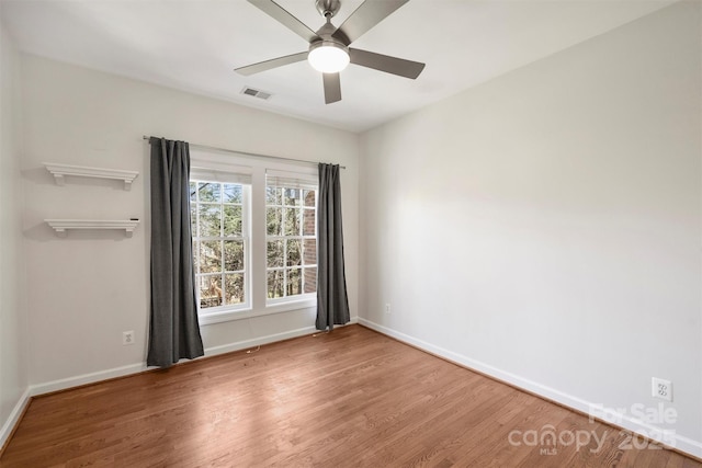 spare room featuring visible vents, ceiling fan, baseboards, and wood finished floors