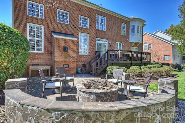 rear view of house featuring crawl space, an outdoor fire pit, a wooden deck, and brick siding