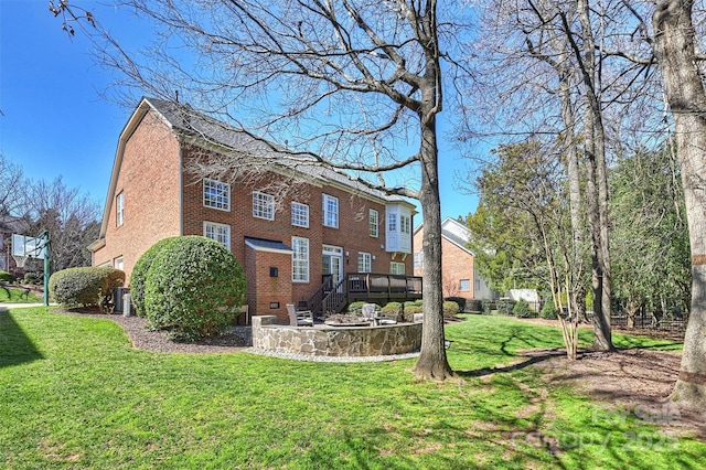 rear view of property featuring a yard, stairway, a deck, and brick siding