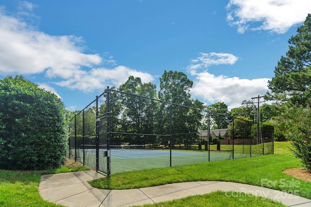 view of sport court featuring fence and a lawn