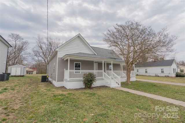 view of front of home featuring an outbuilding, a porch, central AC unit, a storage unit, and a front yard