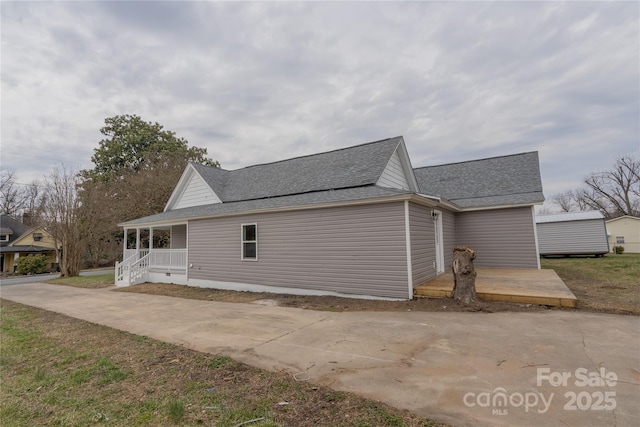 view of property exterior with a porch and roof with shingles