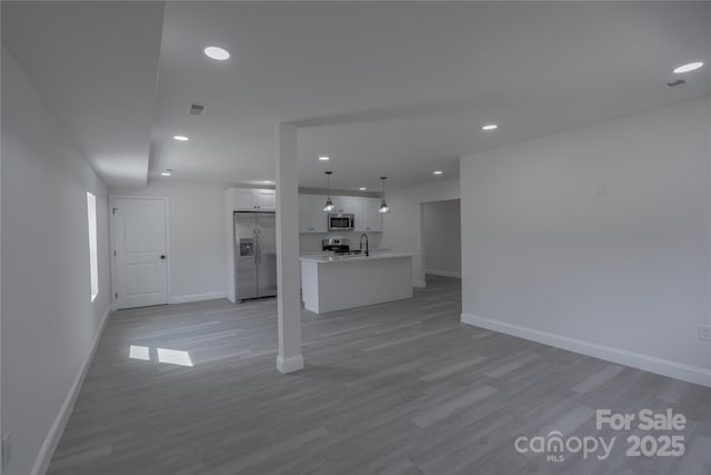 unfurnished living room featuring light wood finished floors, visible vents, and baseboards