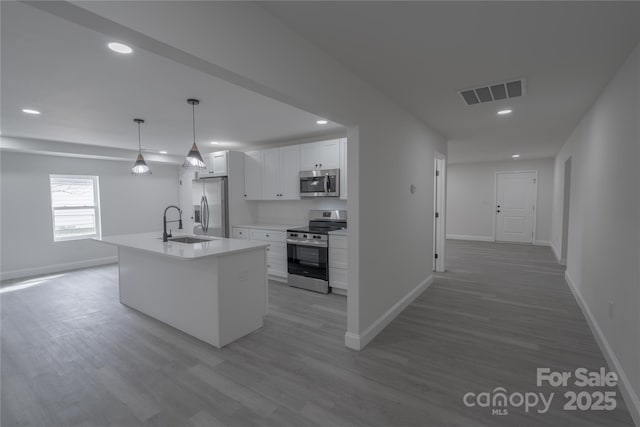 kitchen featuring light wood-type flooring, white cabinetry, visible vents, and appliances with stainless steel finishes