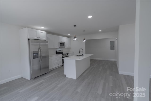 kitchen with light wood-style flooring, stainless steel appliances, a sink, white cabinetry, and light countertops