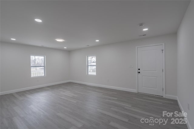 empty room with plenty of natural light, wood finished floors, and baseboards