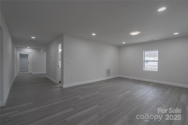 empty room featuring baseboards, visible vents, wood finished floors, and recessed lighting