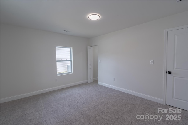 spare room with baseboards, visible vents, and light colored carpet