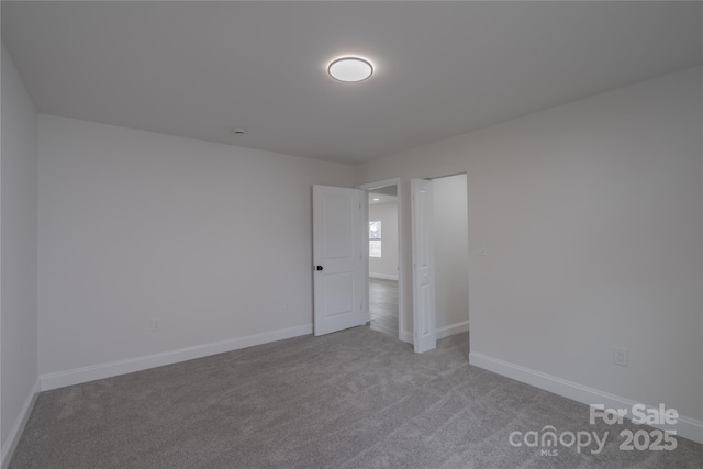 empty room featuring baseboards and carpet flooring