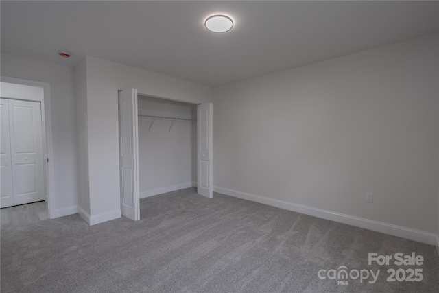 unfurnished bedroom featuring carpet floors, baseboards, and a closet