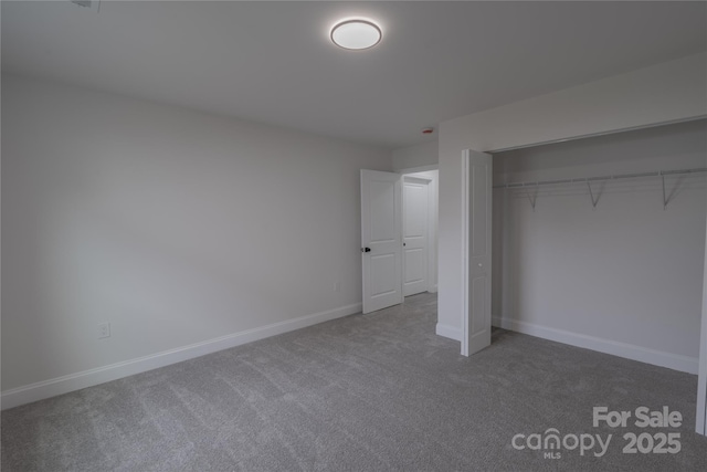 unfurnished bedroom featuring a closet, baseboards, and carpet flooring