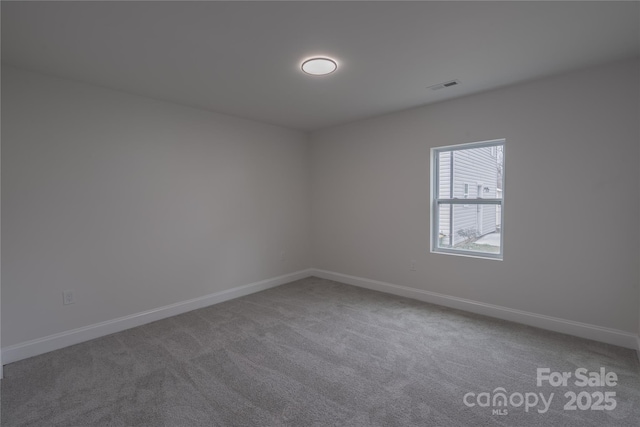 spare room featuring carpet floors, visible vents, and baseboards