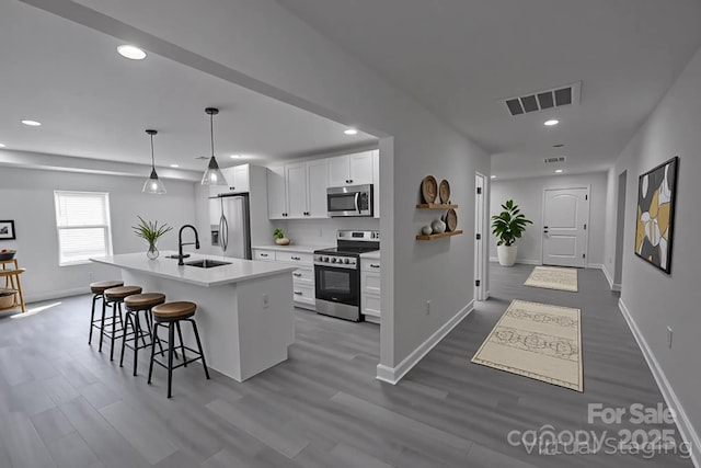 116 11th St, Spencer, NC 28159 - kitchen with stainless steel appliances, dark wood-type flooring, a breakfast bar, white cabinets, and recessed lighting